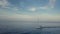 Stunning orbit 4k aerial of sailing boat through blue sea in sunset cloudscape