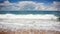 Stunning panoramic view to ocean, empty sandy beach with flowing white foamed water of wave on dramatic clouds background