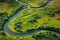 A stunning photo showcasing a peaceful river gracefully running through a vibrant green field, A meandering river cutting through