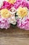 Stunning pink peonies, yellow carnations and roses on rustic woo