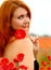 Stunning portrait of a beautiful young redhead woman, look at the camera,  in a black sundress  holding one red poppie. Flowers.