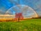 Stunning rainbow over a pink tree at a grassy field in Venango, Pennsylvania