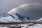 Stunning rainbow in stormy skies over the snow mountains