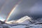 Stunning rainbow in stormy skies over the snowy mountains