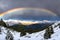 Stunning rainbow in stormy skies over the snowy mountains
