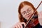 Stunning Redhead Musician Poses with Violin in Captivating Portrait