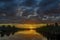 Stunning reflection of sunlight on moving cloud and reflection on the river through the orange horizon in beatiful summer day