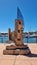 Stunning sculpture stands in the foreground of a bustling harbor and waterfront: Raby Bay Harbour