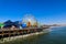 A stunning shot of a colorful Ferris wheel, rollercoaster and carnival games on a long brown wooden pier