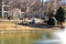 A stunning shot of a gray great white heron bird in flight over a lake with a water fountain in the center of the water