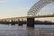 A stunning shot of a long metal bridge over the Mississippi river at sunset with cars and semi trucks