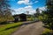 A stunning shot of powerful clouds and and blue sky over a covered brown wooden bridge in the park