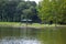 A stunning shot of a rippling green lake with a blue and black pergola on the banks of the lake surrounded by lush green grass