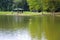 A stunning shot of a rippling green lake with a blue and black pergola on the banks of the lake surrounded by lush green grass