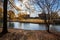 A stunning shot of the still blue lake water surrounded by gorgeous autumn trees in the park with a view of The Parthenon