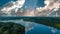 A stunning shot of the still blue waters of the lake with blue sky and clouds reflecting off the water and of lush green trees