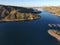 A stunning shot of the still lake waters and sand beach with majestic mountain ranges with blue sky