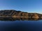 A stunning shot of the still lake waters and sand beach with majestic mountain ranges with blue sky