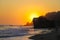 A stunning shot of the sunset and the ocean and the rock and people walking on the beach at El Matador beach