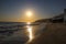 A stunning shot of the sunset and the ocean and the rock and people walking on the beach at El Matador beach