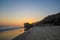 A stunning shot of the sunset and the ocean and the rock and people walking on the beach at El Matador beach