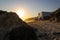 A stunning shot of the sunset peeking over the rocks with a home on the beach under construction at El Matador beach