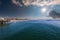 A stunning shot of vast blue ocean water and the cityscape along the beach with brown sand, hotels and buildings