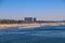 A stunning shot of vast blue ocean water and the cityscape along the beach with brown sand, hotels and buildings