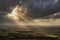 Stunning Summer landscape image of escarpment with dramatic storm clouds and sun beams streaming down