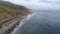 A stunning summer landscape at long the coastline with vast blue ocean water and waves rolling into the shore