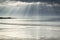 Stunning sun rays bursting from sky over empty yellow sand beach