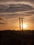 Stunning sun set over field and metal wooden poles electricity t