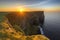 stunning sunrise over a towering cliff, with the sun rising in the distance