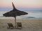 Stunning sunrise with a traditional straw beach umbrella and two deckchairs facing the peaceful Indian Ocean coast, Anakao, Madaga