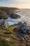 Stunning sunset landscape image of Cornwall cliff coastline with tin mines in background viewed from Pendeen Lighthouse headland