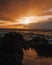 Stunning sunset over a rocky beach shoreline, with the glistening ocean waters in the background