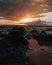 Stunning sunset over a rocky beach shoreline, with the glistening ocean waters in the background