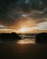 Stunning sunset over a rocky beach shoreline, with the glistening ocean waters in the background