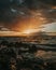 Stunning sunset over a rocky beach shoreline, with the glistening ocean waters in the background