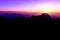 A stunning sunset or sunrise scene of silhouette mountain peaks with blue and purple ridges and twilight background, the purple