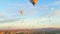 Stunning sunset viewed from bird's eye perspective showing numerous colourful hot air ballon flying over Cappadocia