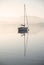 Stunning unplugged fine art landscape image of sailing yacht sitting still in calm lake water in Lake District during peaceful