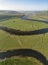 Stunning unusual aerial drone vertical panorama landscape image of meandering river through marshland at sunrise