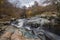 Stunning vibrant landscape image of Aira Force Upper Falls in Lake District during colorful Autumn showing