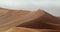 Stunning view on a massive sand dune with lots of tourists walking on it, 4k