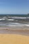 Stunning view of the ocean calm surf with quiet waves reaching the sandy shore and clear turquoise water and clear skies