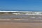 Stunning view of the ocean calm surf with quiet waves reaching the sandy shore and clear turquoise water and clear skies