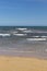 Stunning view of the ocean calm surf with quiet waves reaching the sandy shore and clear turquoise water and clear skies