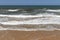 Stunning view of the ocean calm surf with quiet waves reaching the sandy shore and clear turquoise water and clear skies