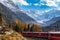 Stunning view of red Rhaetian train running under the Morteratsch Glacier, Grisons, Switzerland